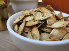 a white bowl filled with some kind of food on top of a wooden table next to two cups