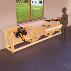 a man standing next to a workbench with tools on it in front of a window