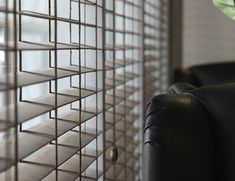 a black leather couch sitting next to a window covered in blinds