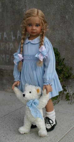 a doll is holding a white teddy bear