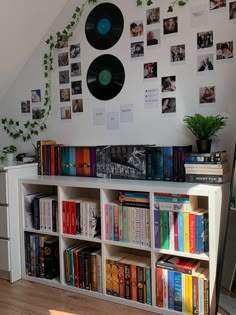 there is a book shelf with many books and vinyl records on the wall above it