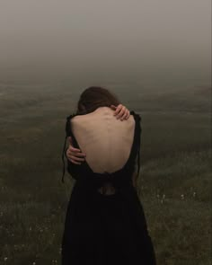 a woman with her back to the camera in a foggy field, looking down