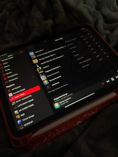 an open laptop computer sitting on top of a bed covered in black and red blankets