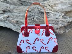 a red and white handbag with candy canes on it sitting on a wooden table