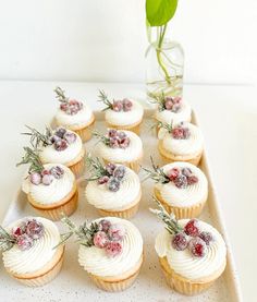 there are many cupcakes with white frosting and berries on the top one