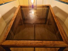 a wooden table with a glass top in a room that has white walls and wood flooring