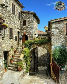 an alley way with stone buildings and plants growing on the steps leading up to it