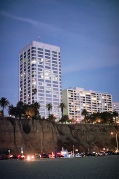 a tall white building sitting on top of a cliff next to a beach at night