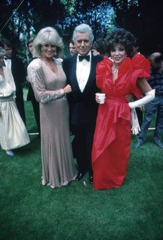 three people standing next to each other in formal wear on the grass at an outdoor event