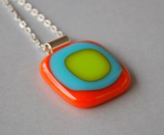 an orange, blue and green necklace on a silver chain