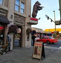 there is a bear statue on top of a sign in front of a building that says grizzly's