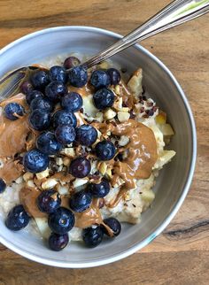 a bowl filled with oatmeal and blueberries on top of a wooden table