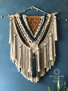 a wall hanging made with macrami and tassels on a blue wall