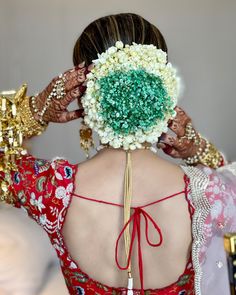 the back of a woman's head with flowers in her hair and jewelry around her neck