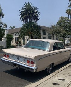 an old car is parked on the side of the road in front of a house