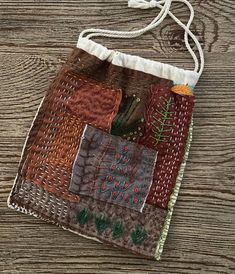 a small bag made out of patchwork material on a wooden surface with string hanging from it