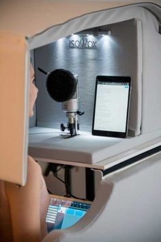 a person looking at a computer screen with a microphone in front of them and a tablet on the desk