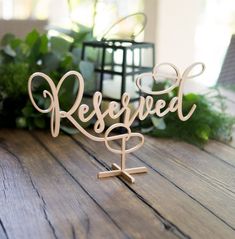 a wooden sign that says reserved on it sitting on a table next to some plants