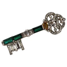 Trifari Sterling Vermeil Jeweled Key Brooch by Alfred Philippe from the 1940's with emerald and citrine crystals. 2.6" x .95". 1940's USA. Marked: Trifari with Crown, Sterling Reference: Brunialti, American Costume Jewelry - Art and Industry (2008) Vol 2 p 138, feature in Women's Wear Daily, 3 Sept. 1943, p 11, showing and dating this design. American Costume, Womens Wear Daily, Daily 3, Art And, Citrine Crystal, Women's Wear, Vol 2, Vintage Brooches, Costume Jewelry