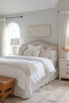 a bedroom with white bedding and curtains