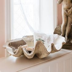 a statue is sitting on top of a window sill next to a book case