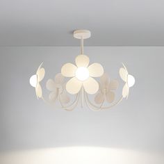 a white flower shaped light fixture hanging from the ceiling in a room with gray walls