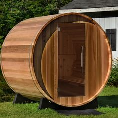 a wooden barrel sauna outside in the grass