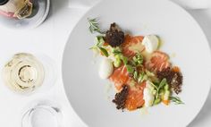 a white plate topped with lots of food next to a glass of wine and a bottle