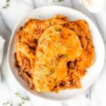 a white bowl filled with chicken and cheese casserole on top of a table