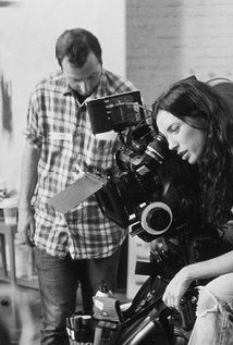 black and white photograph of two people in a room with a camera on a tripod