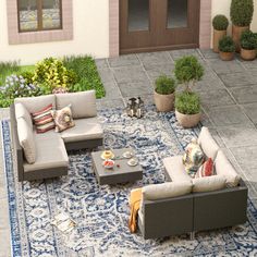 an outdoor living area with couches, tables and potted plants