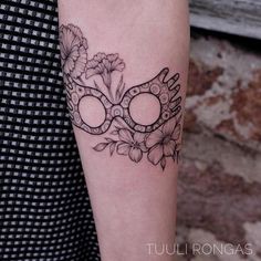 a woman with a tattoo on her arm wearing a masquerade mask and flowers