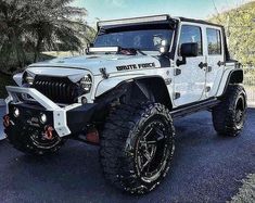 a white jeep parked in a parking lot with palm trees and blue sky behind it