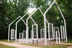 a group of white windows sitting in the middle of a park with trees behind them