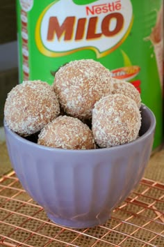 a bowl filled with powdered donuts on top of a table next to a bottle of milk