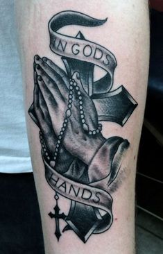 a black and white tattoo with an image of two hands holding a cross, in god's hands