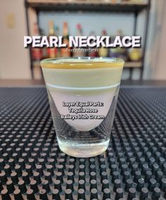 a shot glass sitting on top of a table with the words pearl necklace in it