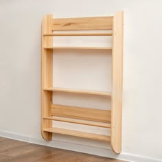 a wooden shelf sitting on top of a hard wood floor next to a white wall