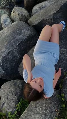 a woman laying on top of a pile of rocks