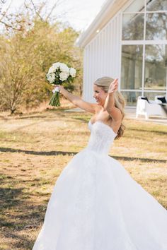 a woman in a white wedding dress is holding her bouquet and waving to the side