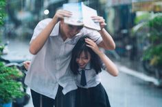 two people are standing in the rain with umbrellas over their heads and one person is covering her head