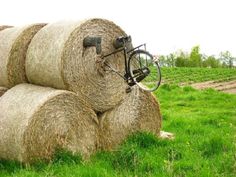 a bicycle is parked on top of hay bales in a field with green grass