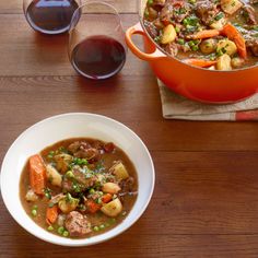 a bowl of stew next to two glasses of wine