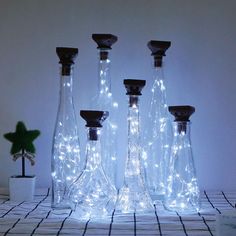 three glass bottles with lights in them sitting on a table