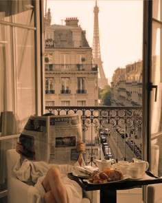 a person sitting on a couch reading a newspaper in front of the eiffel tower