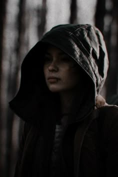 a woman wearing a hooded jacket in the woods