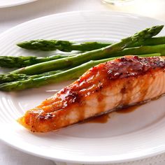 a piece of salmon and asparagus on a white plate with sauce in the middle