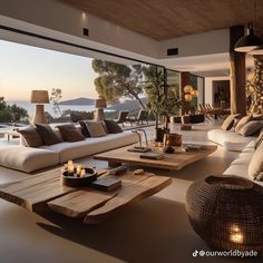 a living room filled with lots of furniture next to a large glass window overlooking the ocean