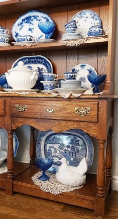 an old china cabinet with blue and white dishes on it's shelf, next to a wooden hutch