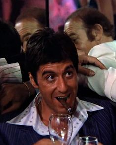 a man holding a wine glass in front of his face and making a funny face